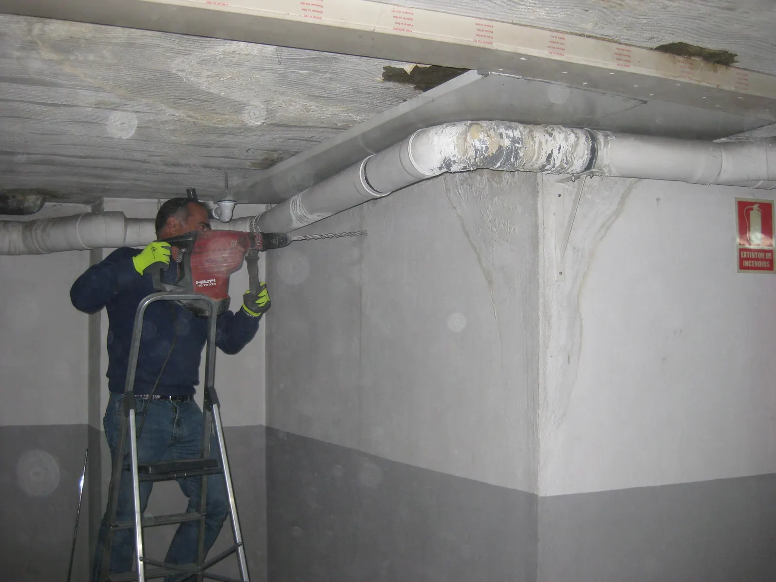 Operario perforando el muro del garaje junto al forjado