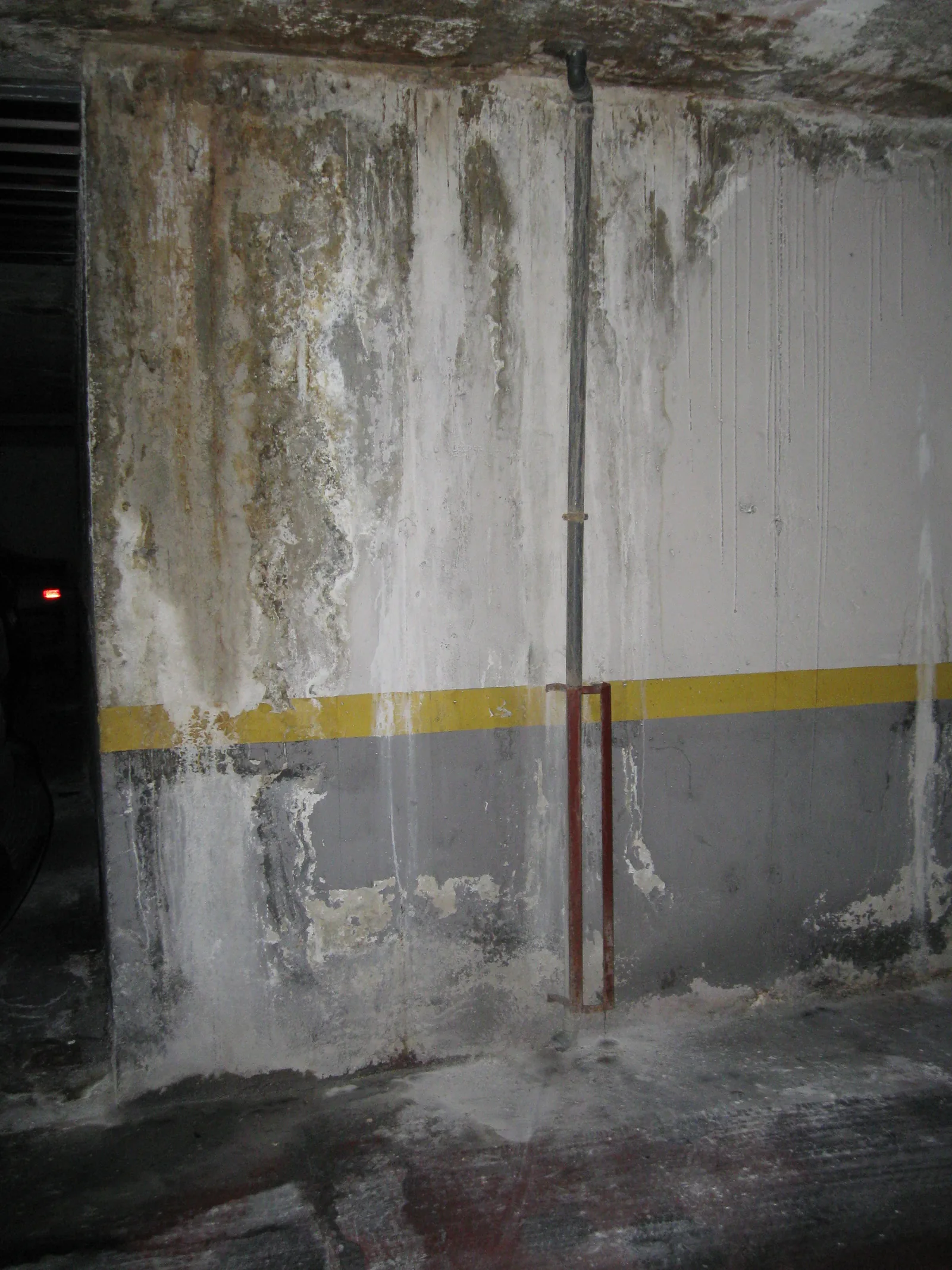 Muro de garaje comunitario con eflorescencias y regueros de agua descendiendo hasta la solera